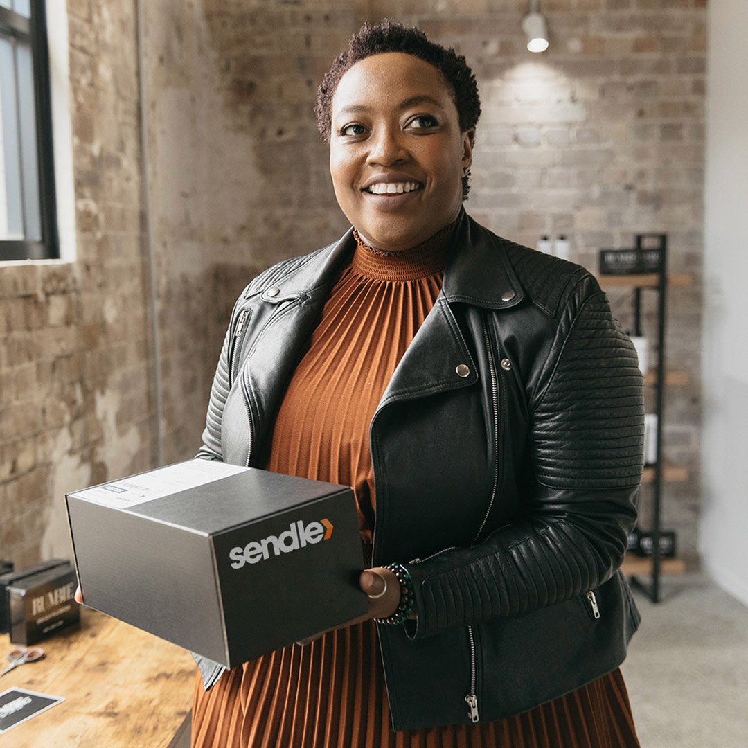 A black woman with a small business holding a Sendle package