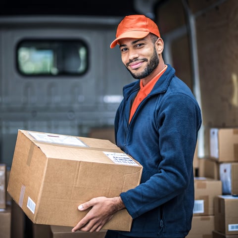 A delivery man smiling holding a package