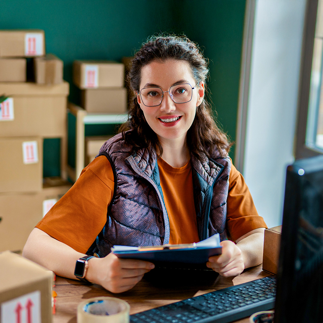 sendle-in-office-logistic-woman-smiling-surrounded-by-parcels
