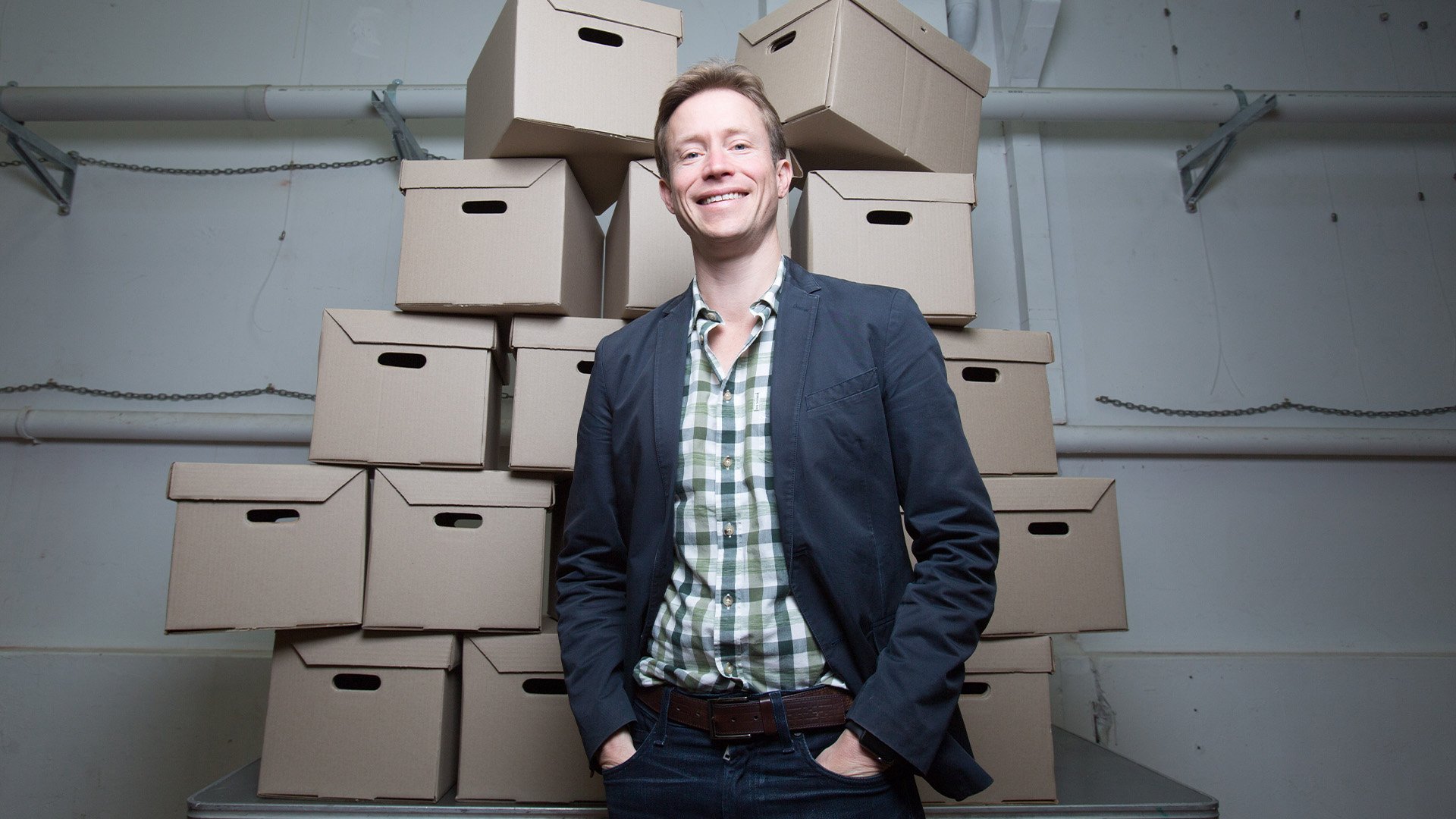 Sendle CEO Founder James Chin Moody standing behind stack of boxes