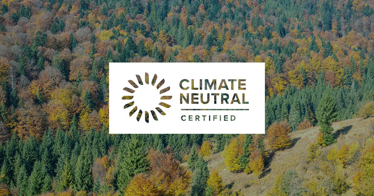 climate neutral certified label white over autumn colorful lush tree forest background